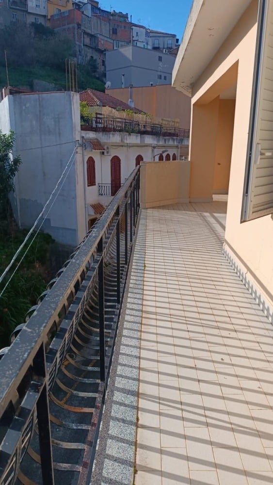 Ampio balcone con vista sulla città, pavimento in piastrelle chiare e ringhiera in ferro battuto, ideale per godersi l'aria aperta e il panorama urbano.
