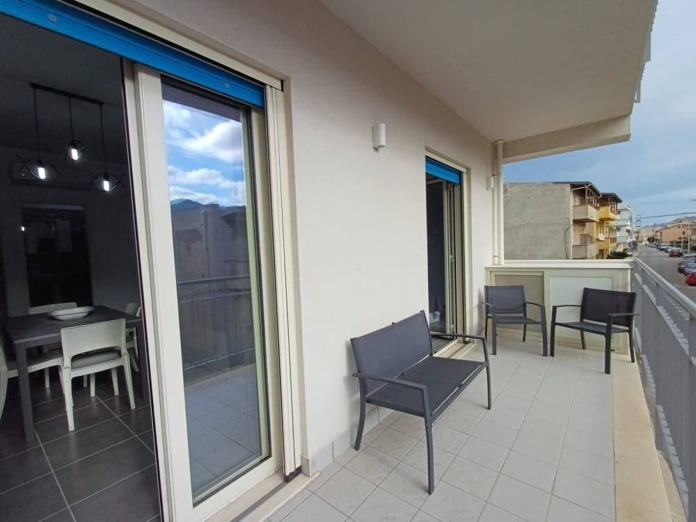 Balcone di appartamento con sedie e vista sulla strada, con porta scorrevole e arredamento moderno, ideale per relax all'aperto e vivere in modo confortevole il proprio spazio abitativo.