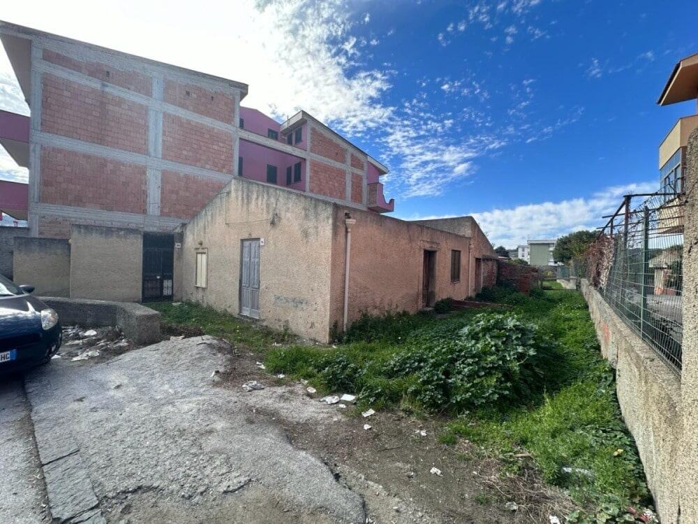 Edificio residenziale in fase di costruzione con area esterna verde e strada asfaltata, ideale per investimenti immobiliari e nuove abitazioni a NextCasa.