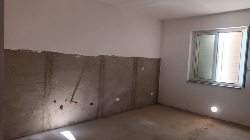 Riparazione e ristrutturazione appartamento con pareti in fase di finitura e ottima illuminazione naturale da finestra, pronto per arredare e abitare situato in zona residenziale.