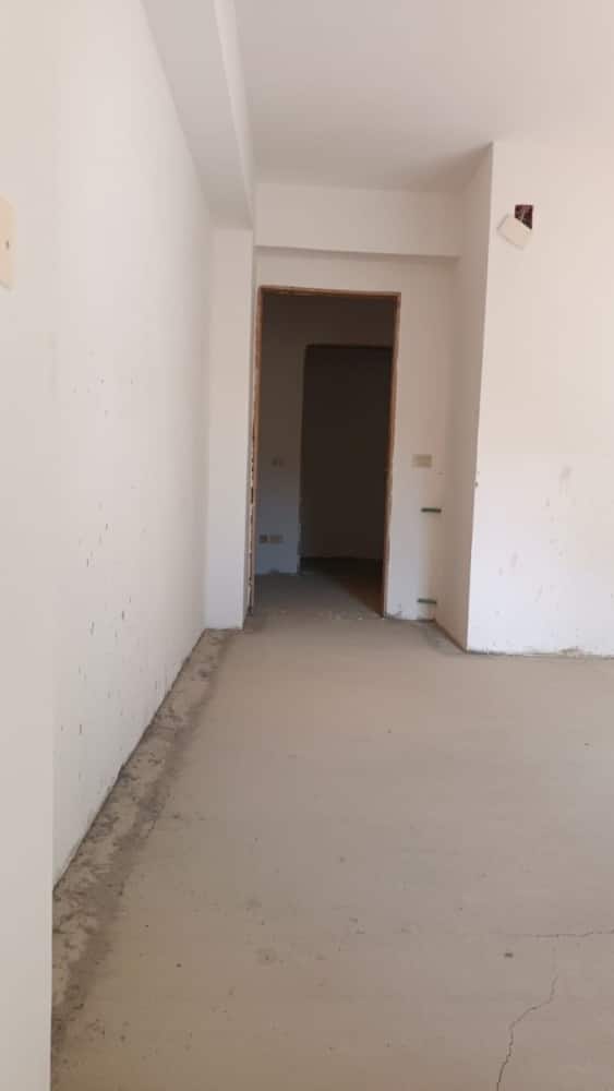 Interno di appartamento in fase di ristrutturazione con pareti bianche e pavimento in cemento grezzo.