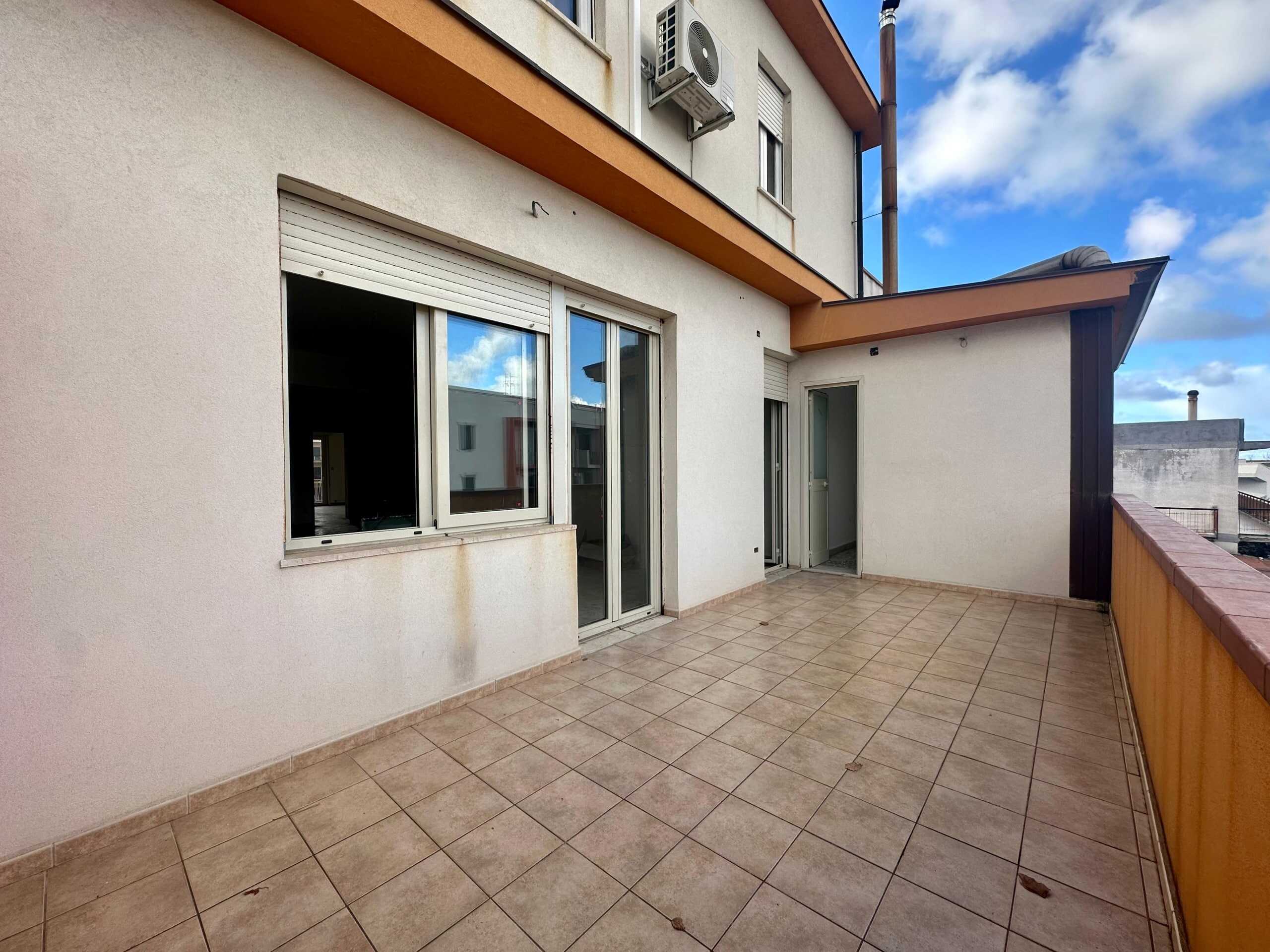 Balcone spazioso con pavimento in piastrelle e vista su edifici residenziali, perfetto per relax e vita all'aperto, esempio di proprietà immobiliare di NextCasa.