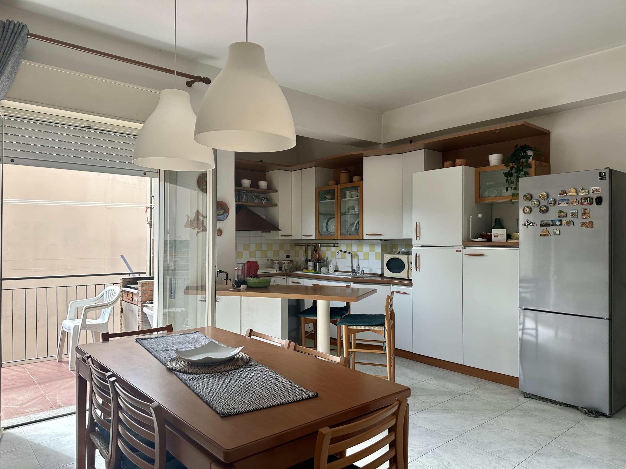 Fornellino con cucina a vista e tavolo da pranzo in affitto, spazio luminoso con accesso al balcone, stile moderno e funzionale, ideale per residenza o investimento immobiliare, ristrutturato.