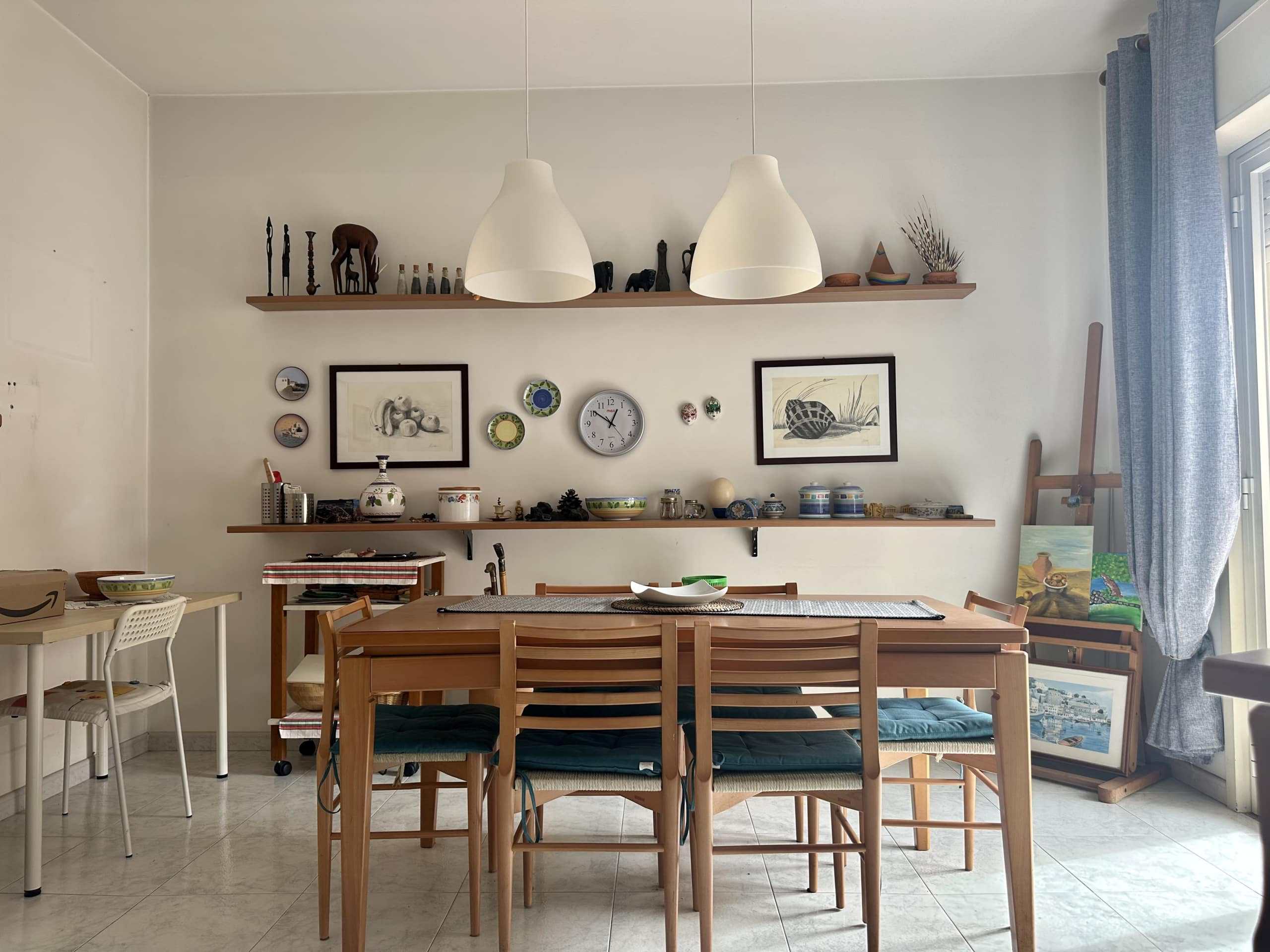 Elegante sala da pranzo e living con mobili in legno, decorazioni artistiche e oggetti di design, atmosfera accogliente e luminosa, perfetta per momenti conviviali e relax in casa.