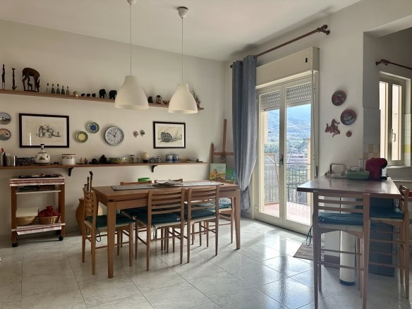 Elegante sala da pranzo con tavolo in legno, grande finestra con vista sulla città e decorazioni artistiche alle pareti, in uno stile accogliente e luminoso, ideale per abitazioni di design.