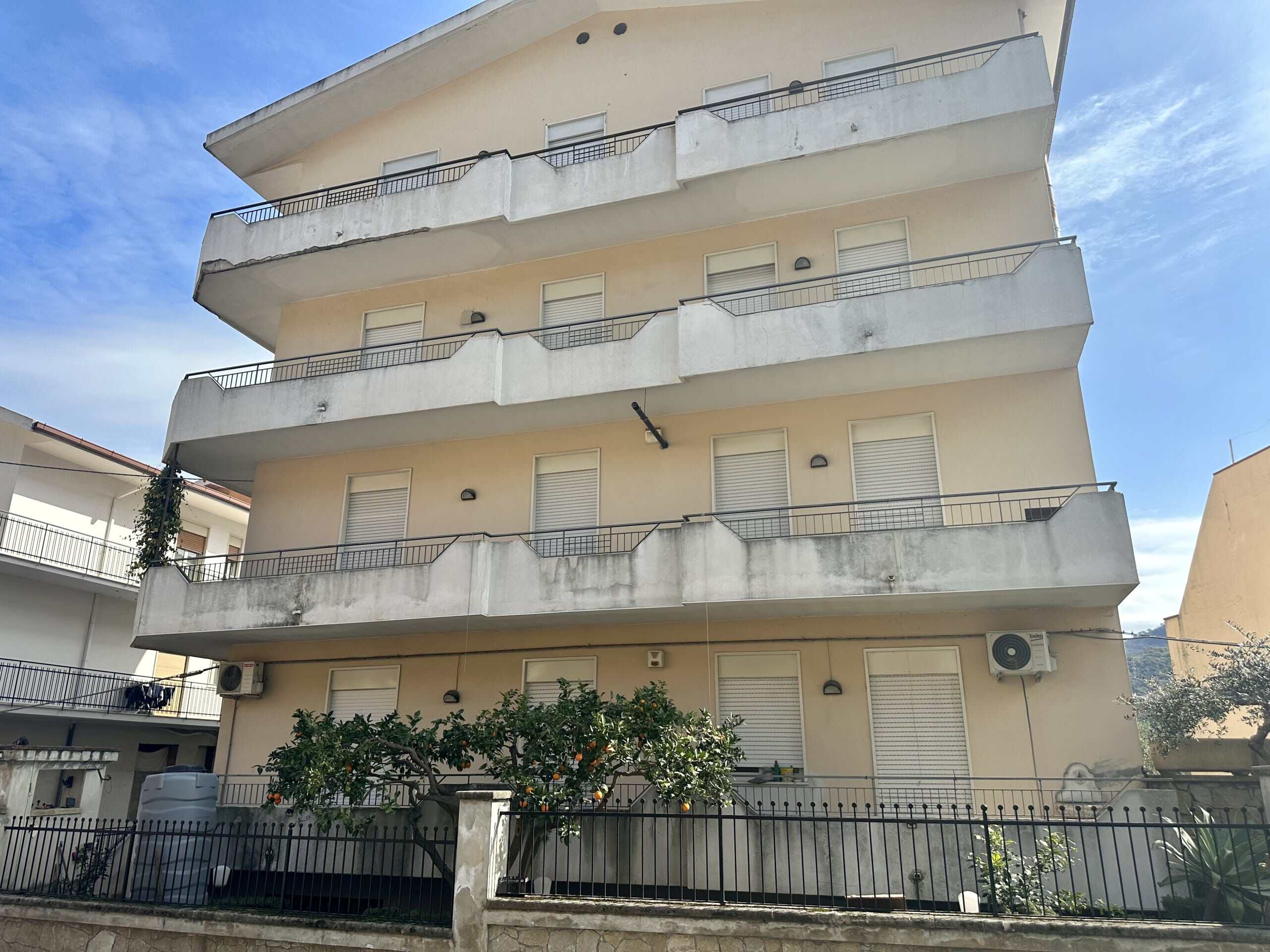 Appartamento residenziale con ampie terrazze, facciata in colore beige e balconi con ringhiera in metallo, aria condizionata esterna, situato in zona tranquilla vicino a servizi e spazi verdi.