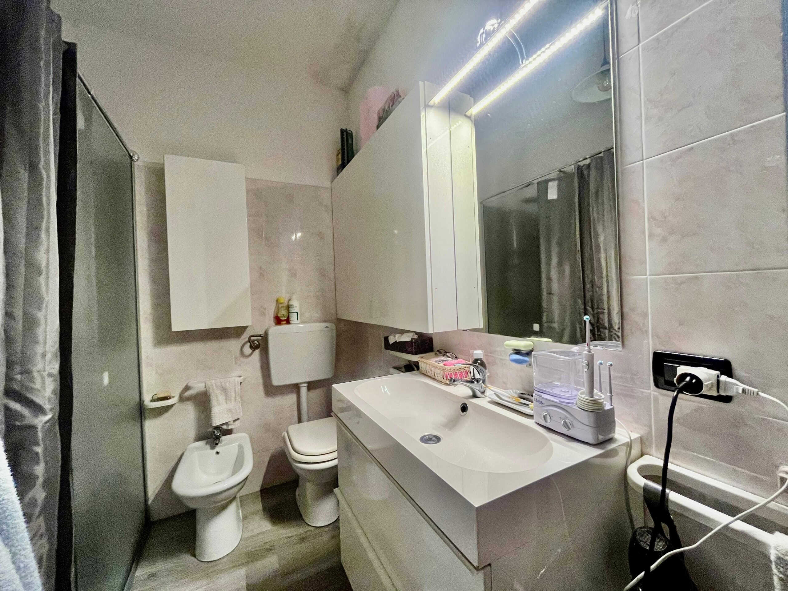 Lavabo e servizi moderni in bagno di design con mobili minimalisti e dettagli funzionali, ideale per appartamenti di ultima generazione o ristrutturazioni specifiche.