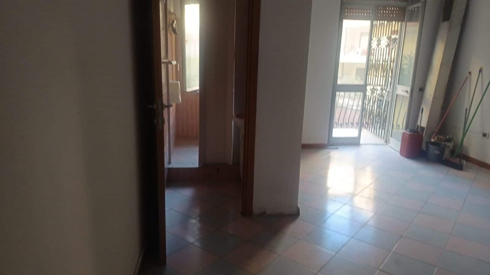 Vani di casa con porta balcone, ingresso luminoso, pavimenti in ceramica, arredamento semplice, affaccio su balcone con vista sulla città, ingresso spazioso, zona giorno ben illuminata, ideale per ristrutturare.