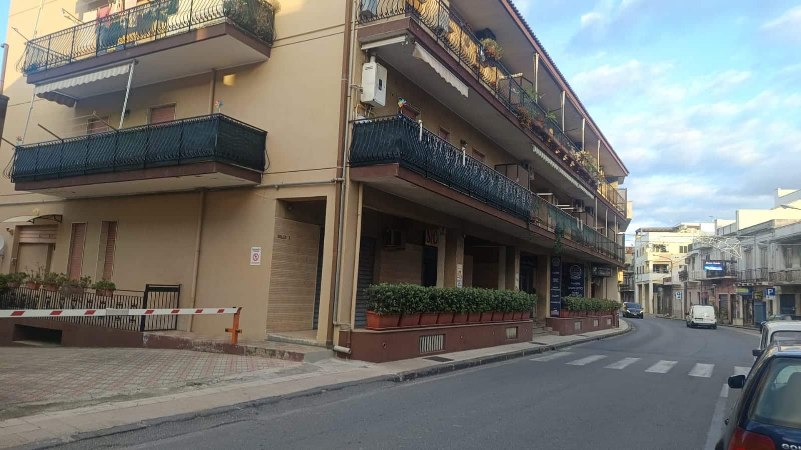 Elegante edificio residenziale con balconi e piante ornamentali, situato in zona centrale di città, ideale per servizi e commercio, con parcheggio gratuito nelle vicinanze.
