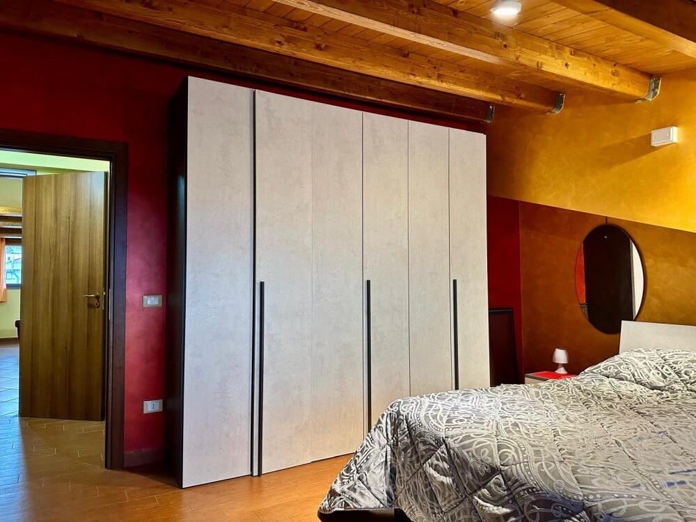 Armadio a parete in camera da letto con pareti colorate, dettagli in legno e decorazioni moderne. Ideal fornisce spazio di archiviazione funzionale e stile contemporaneo per interni raffinati.