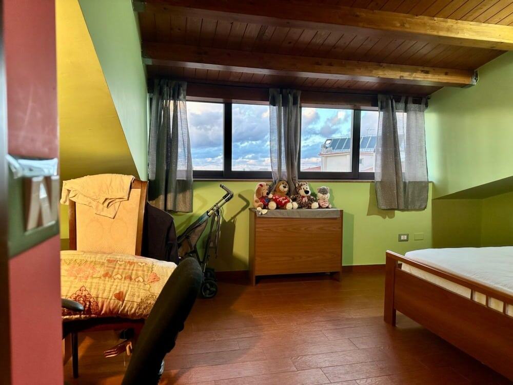 Divano letto con coperte colorate, vista sulle nuvole attraverso grandi finestre in una stanza moderna e accogliente.