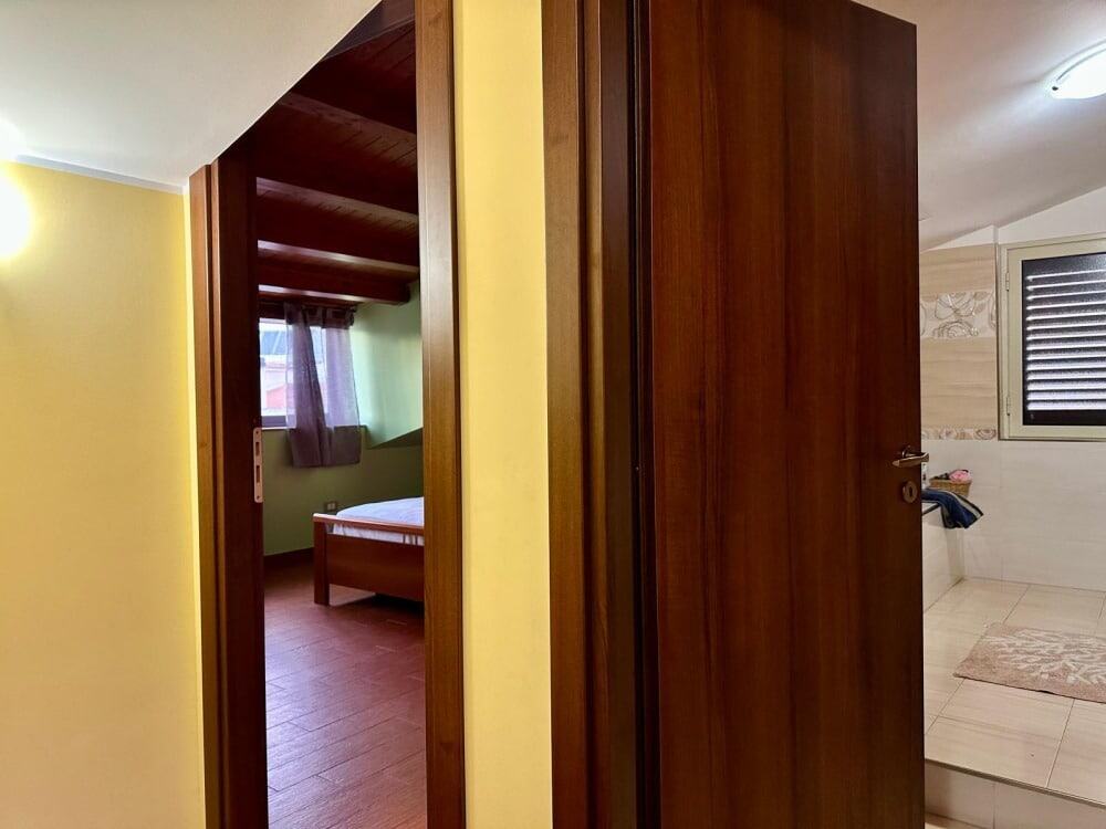 Ampia porta scorrevole in legno che separa la camera da letto dalla zona giorno in un appartamento arredato NextCasa.