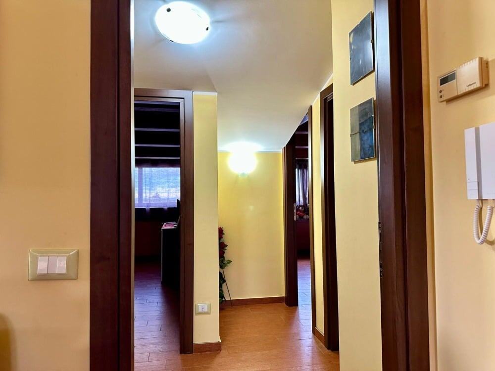 Unicità di un ingresso di casa con pareti color crema e porte in legno scuro, illuminato da luci calde, perfetto per creare un'atmosfera accogliente e elegante in ambienti residenziali NextCasa.
