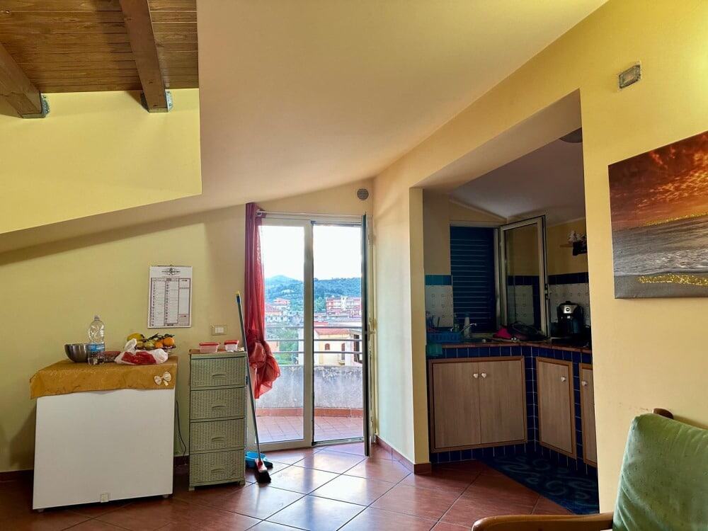 Lampada da parete, vista sulla cucina e sul balcone di un appartamento a NextCasa, con arredamento semplice e vista panoramica sulla città.