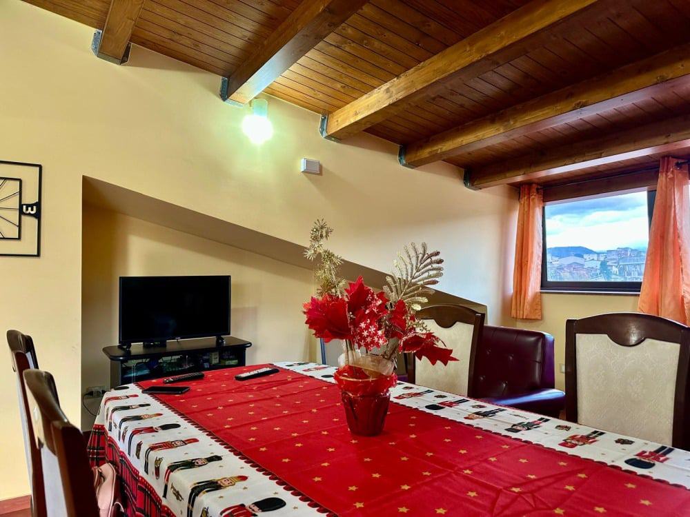 Decorazione natalizia su tavolo, ambiente famigliare con vista sulle montagne, arredamento caldo e accogliente, ideale per case di montagna o appartamenti in affitto a NextCasa.