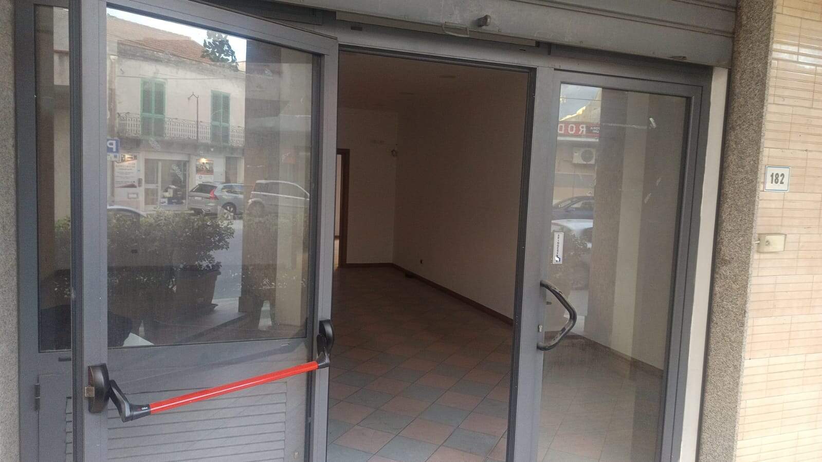 Finestra e portone di ingresso in un immobile commerciale o ufficio, con vetrate e porta scorrevole, pronto per ristrutturazione, in zona urbana.