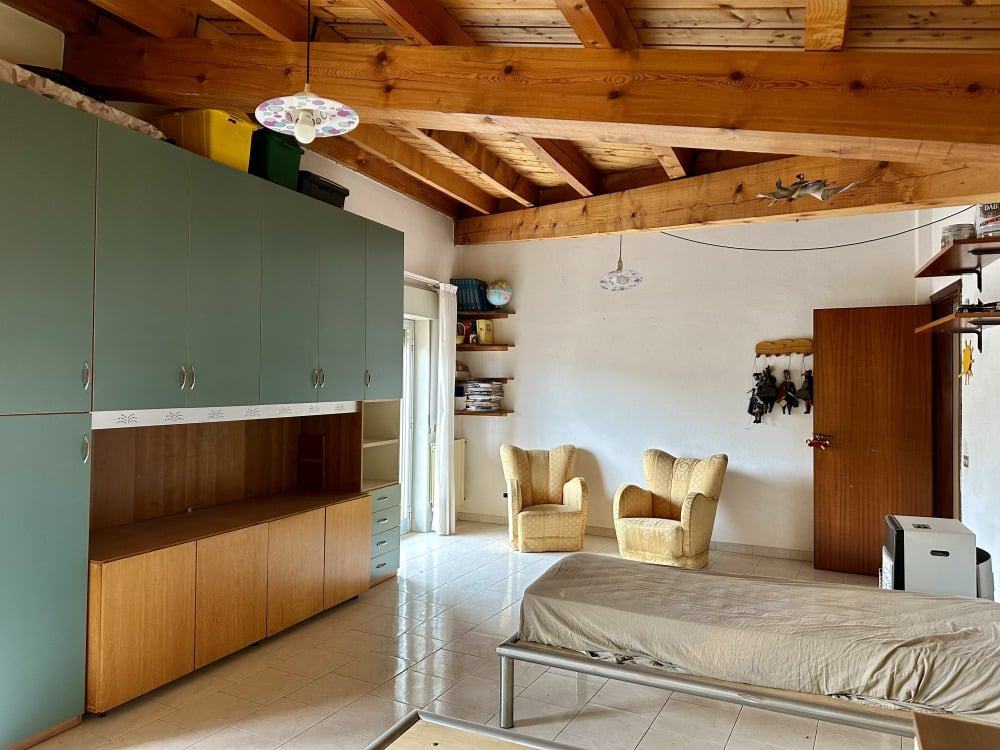 Armadio con ante verde e soggiorno con sedie in poltrona beige in un appartamento indipendente. Spazi luminosi, soffitto in legno e arredi funzionali, ideali per case private e residenze con comfort.