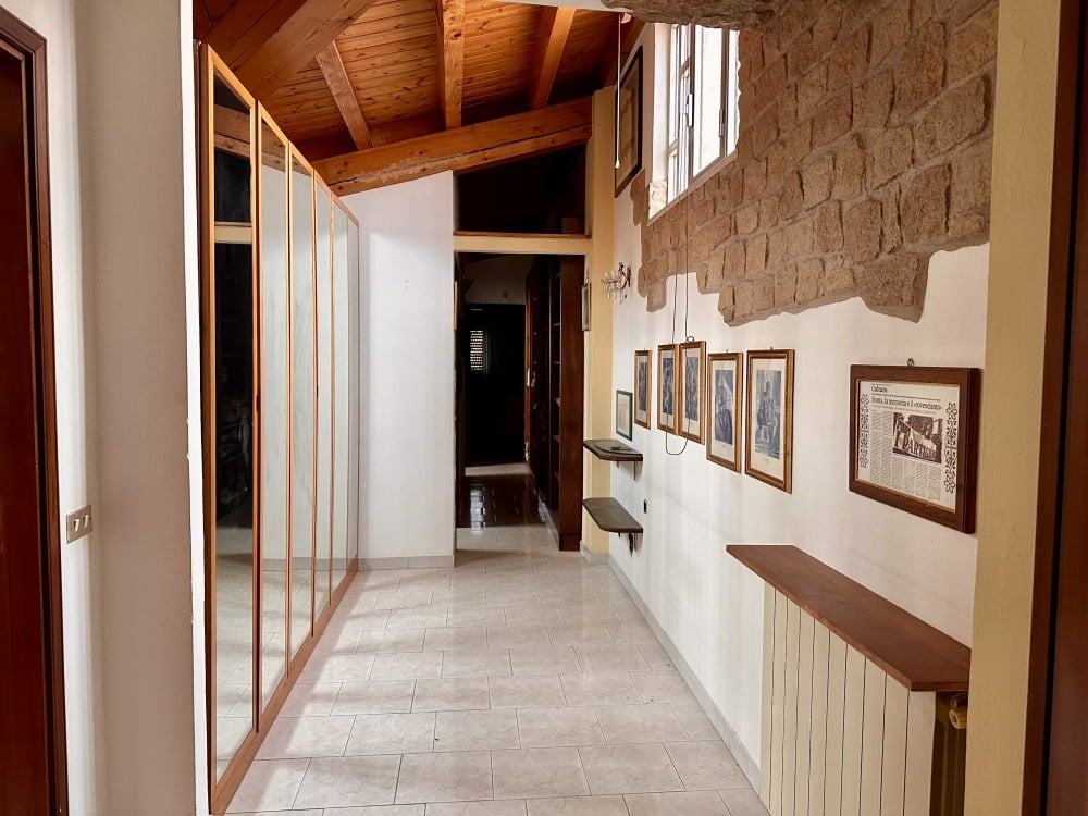 Splendida vista dell'ingresso di una proprietà con pareti in mattoni, soffitto in legno a volta e arredi eleganti, perfetta per la vendita o locazione immobiliare.
