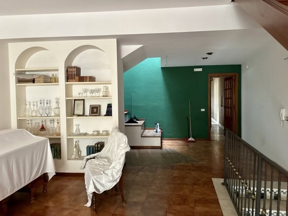 Spazi interni di un appartamento ristrutturato con pareti colorate, scaffale decorativo con oggetti vintage, mobili in legno e piastrelle in stile rustico, atmosfera accogliente e moderna.