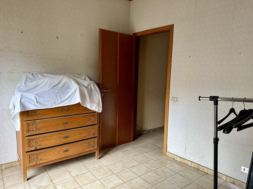 Armadio in legno massiccio con ripiani e decorazioni artigianali, in una stanza arredata e spaziosa.