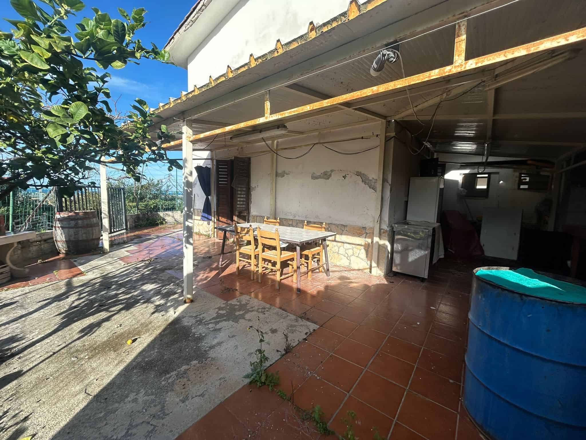 Pozzo rustico con area esterna, tavolo in legno, botti in acciaio, e spazio per relax all'aperto sotto il sole. Ideale per incontri e momenti di convivialità in un ambiente naturale e accogliente.