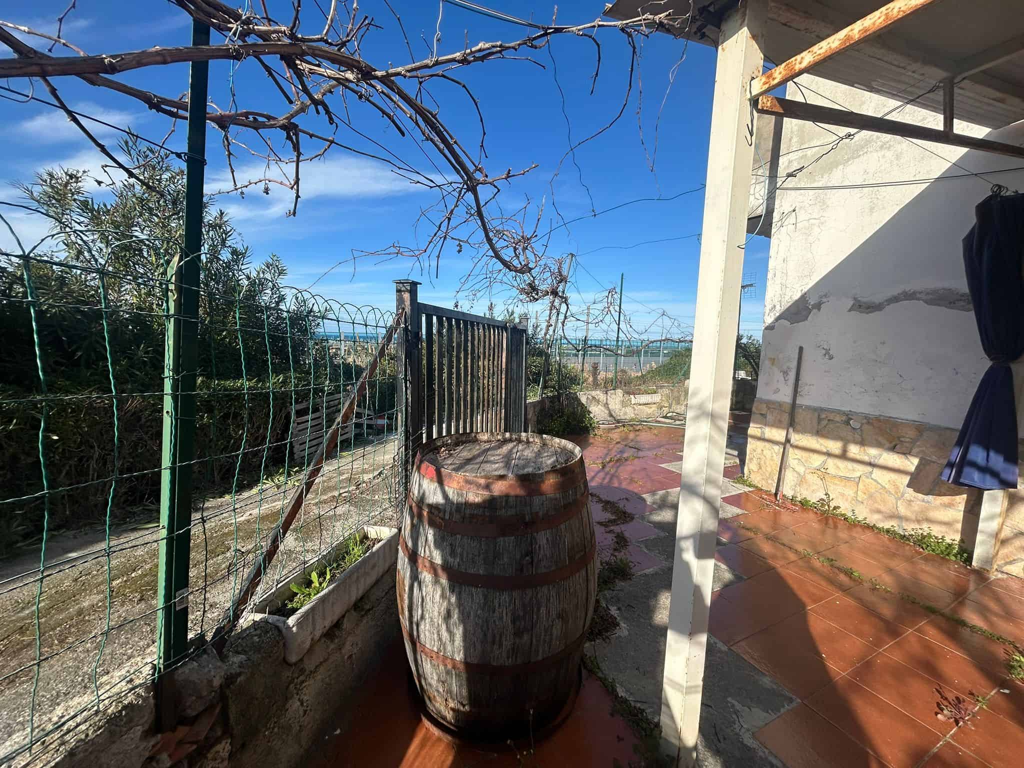 Barile di legno su terrazza con vista su giardino e vigneti, ambiente rustico e accogliente, ideale per momenti di relax all'aperto, privacy e natura, foto di una casa NextCasa in stile agricolo.