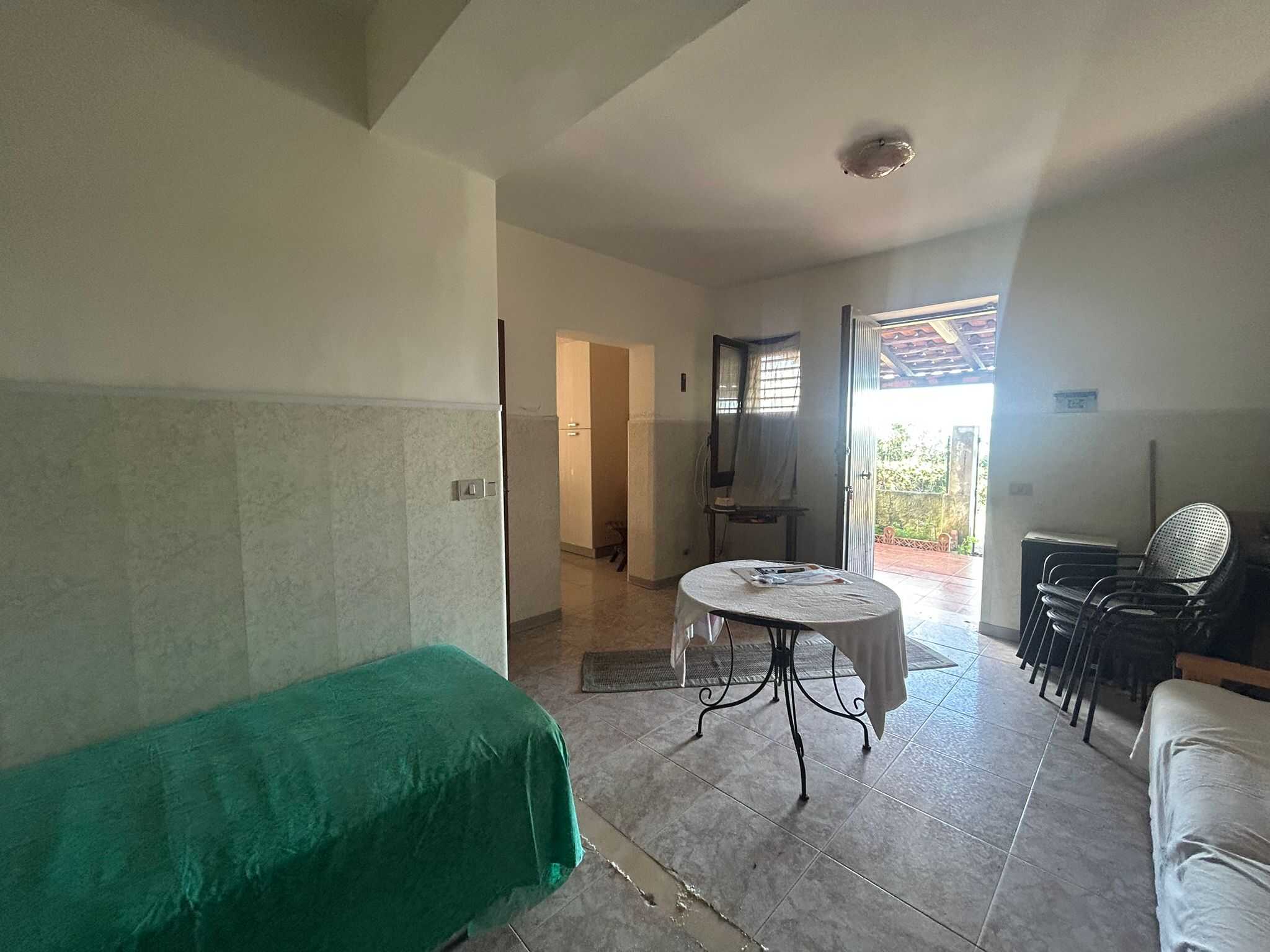 Soggiorno luminoso con accesso al balcone, arredi semplici e pavimenti in piastrelle, ideale per case in vendita o affitto a NextCasa.
