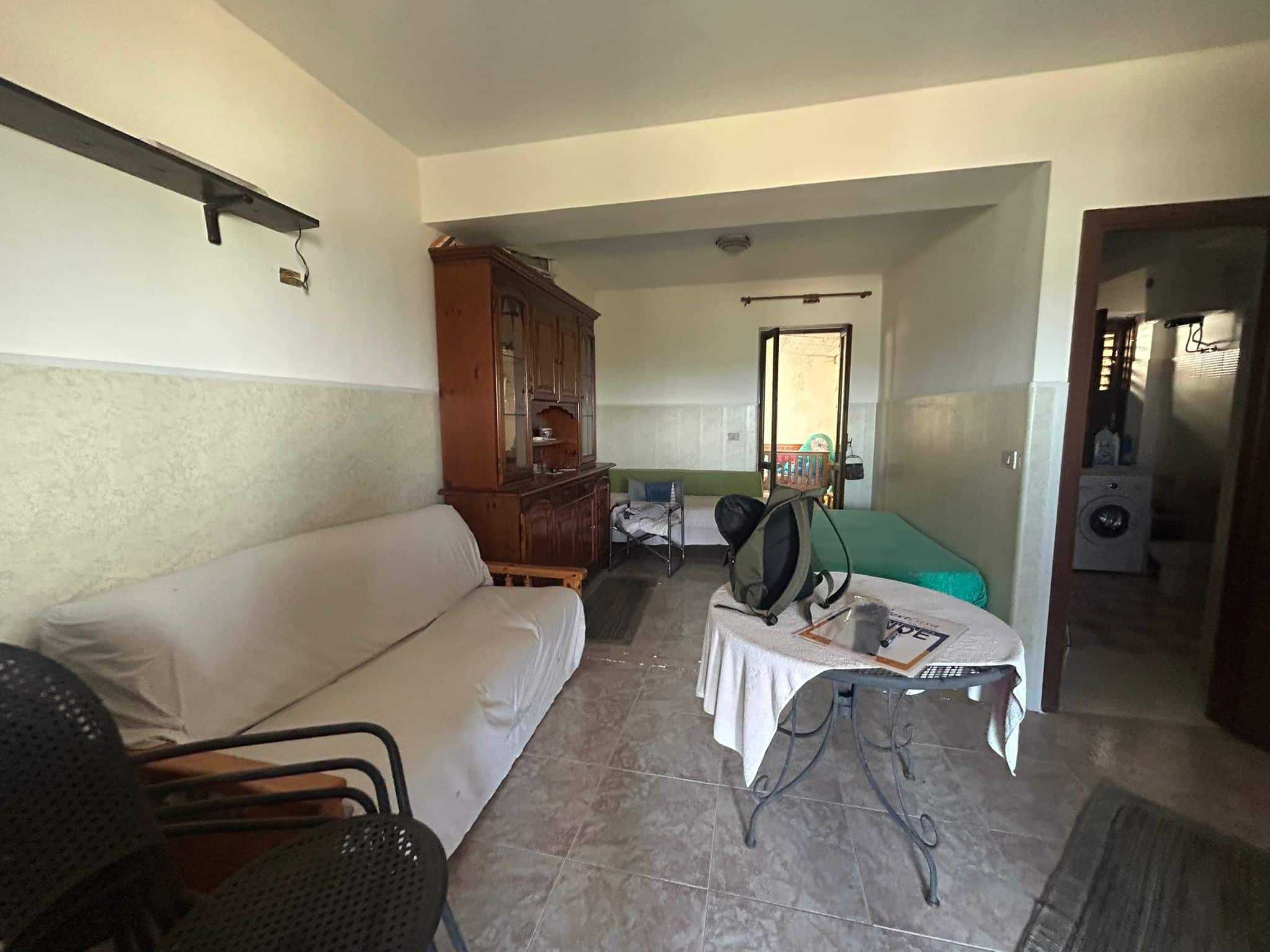 Soggiorno con arredi classici, divano, tavolo con rivestimento in tessuto, mobile antico in legno, camera da letto o zona riposo, ambiente abitabile dotato di ingresso e accesso alla terrazza o balcone.