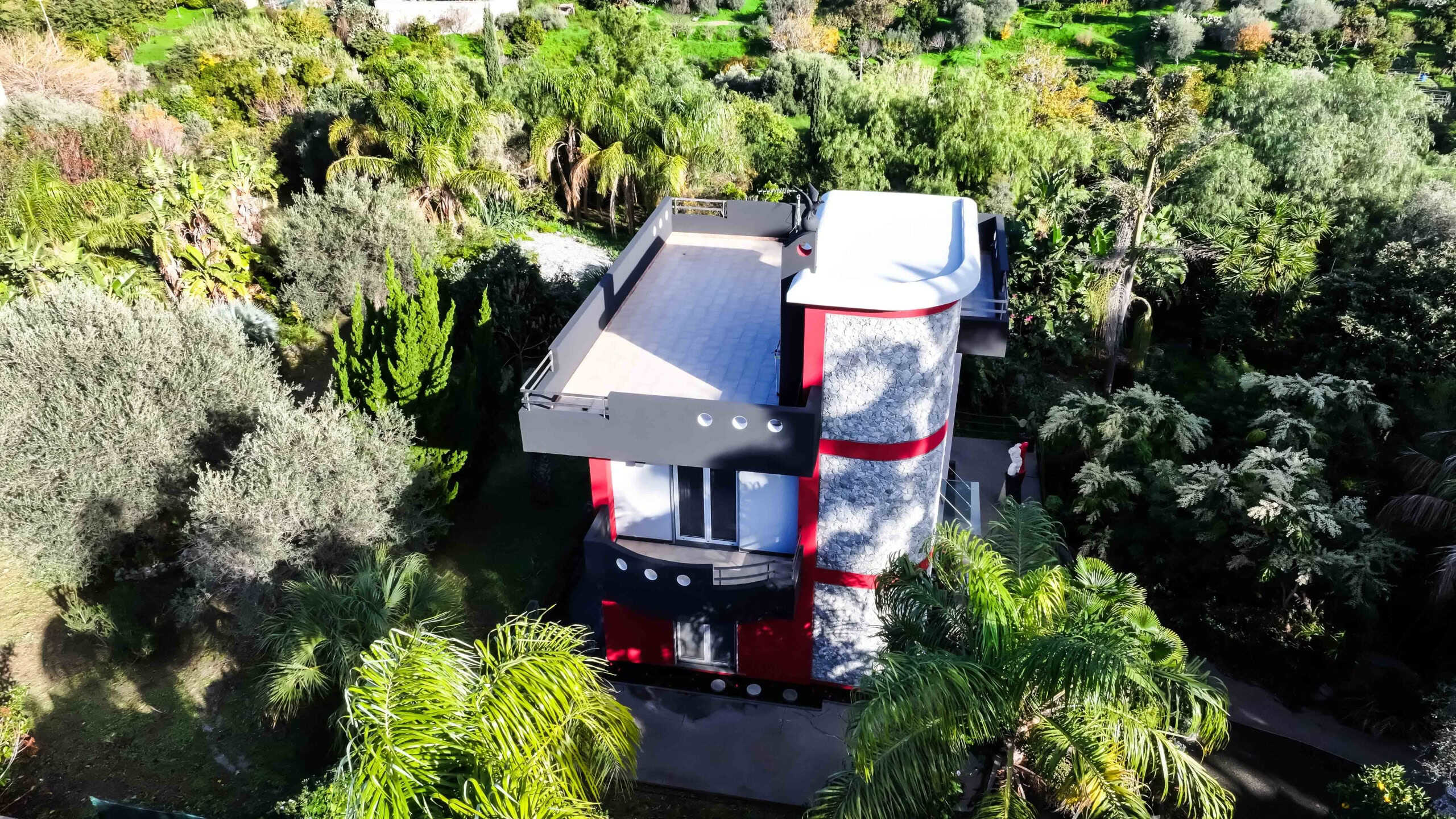 Casa moderna con terrazza panoramica in un giardino tropicale, design innovativo, isolamento acustico e materiali sostenibili, ideale per vivere in armonia con la natura.
