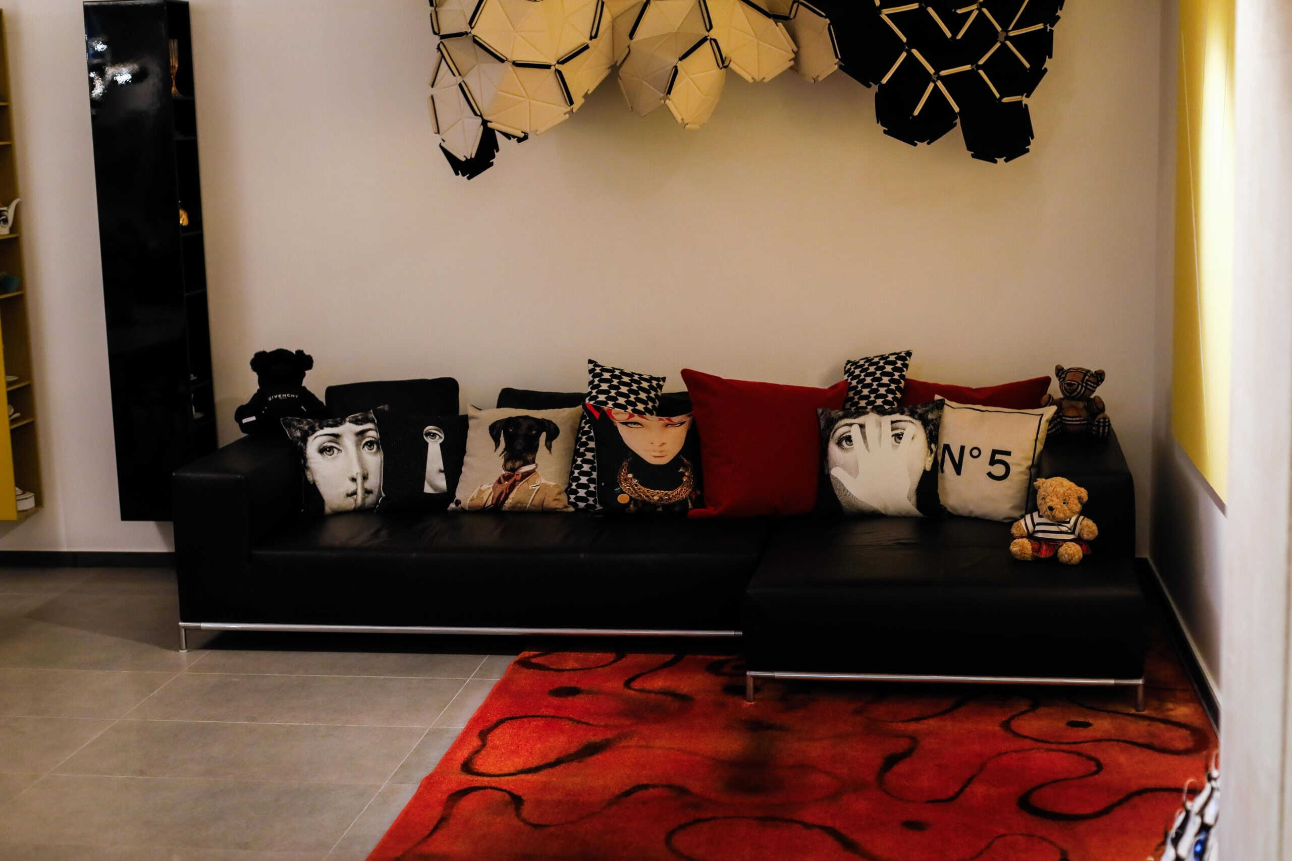 Guanciali decorativi con stampe di moda e arte moderna su divano in pelle nera in salotto alla moda NextCasa.
