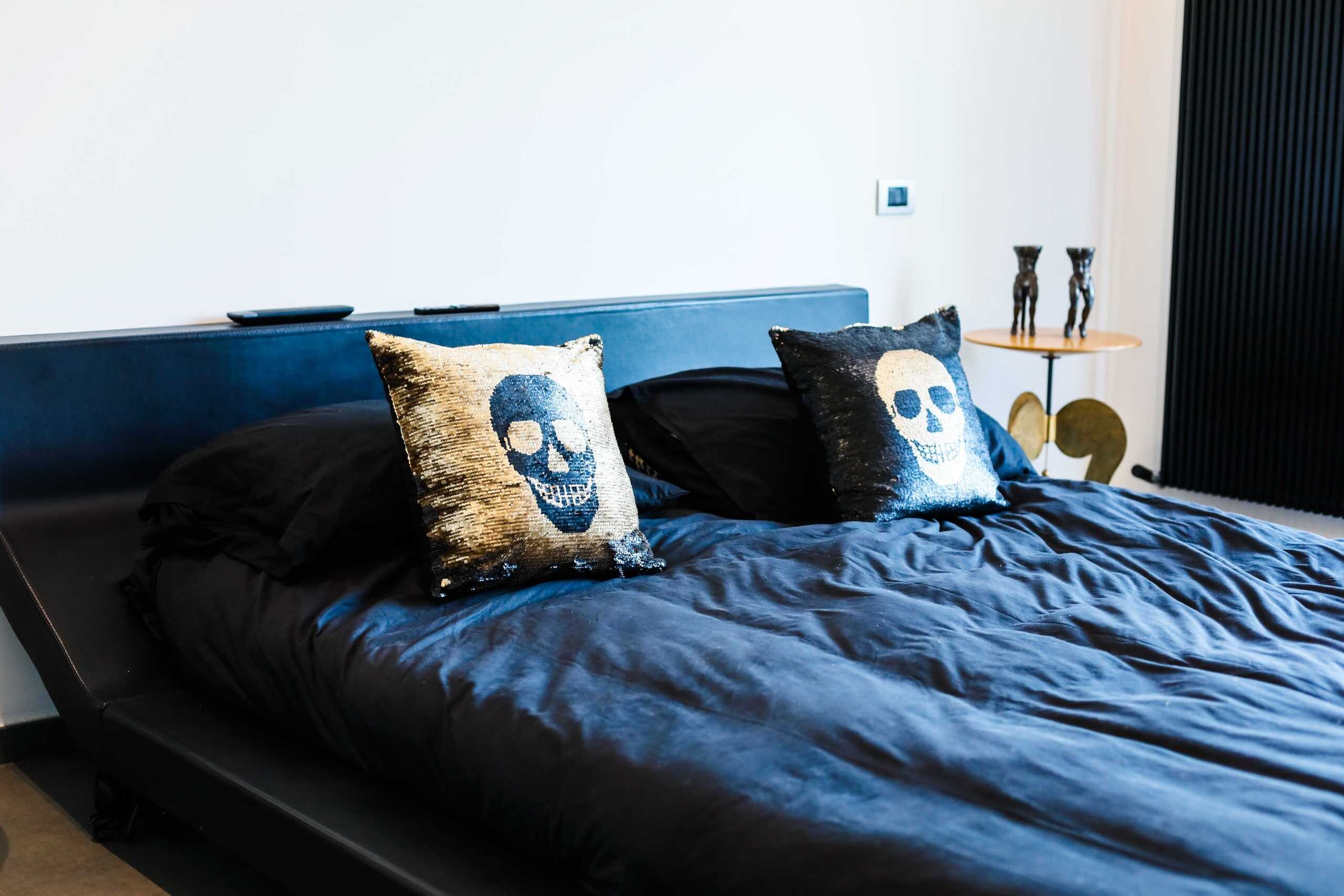 Lenzuola nere con cuscini decorativi a sequin con stampa di teschio, arredamento moderno in camera da letto di lusso.