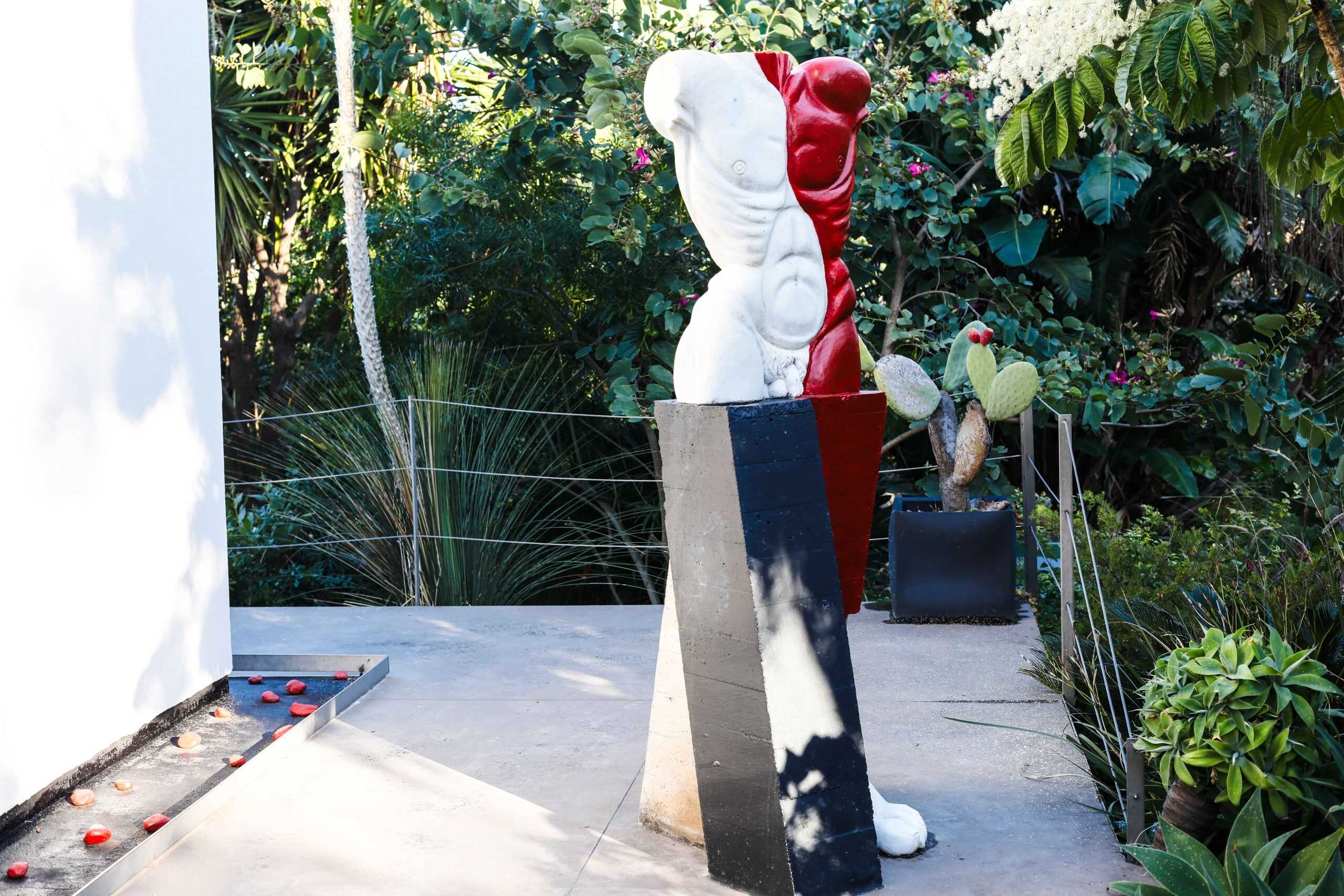 Scultura moderna astratta in giardino con piante tropicali e cactus, decorazione artistica per l'esterno di case e spazi verdi.
