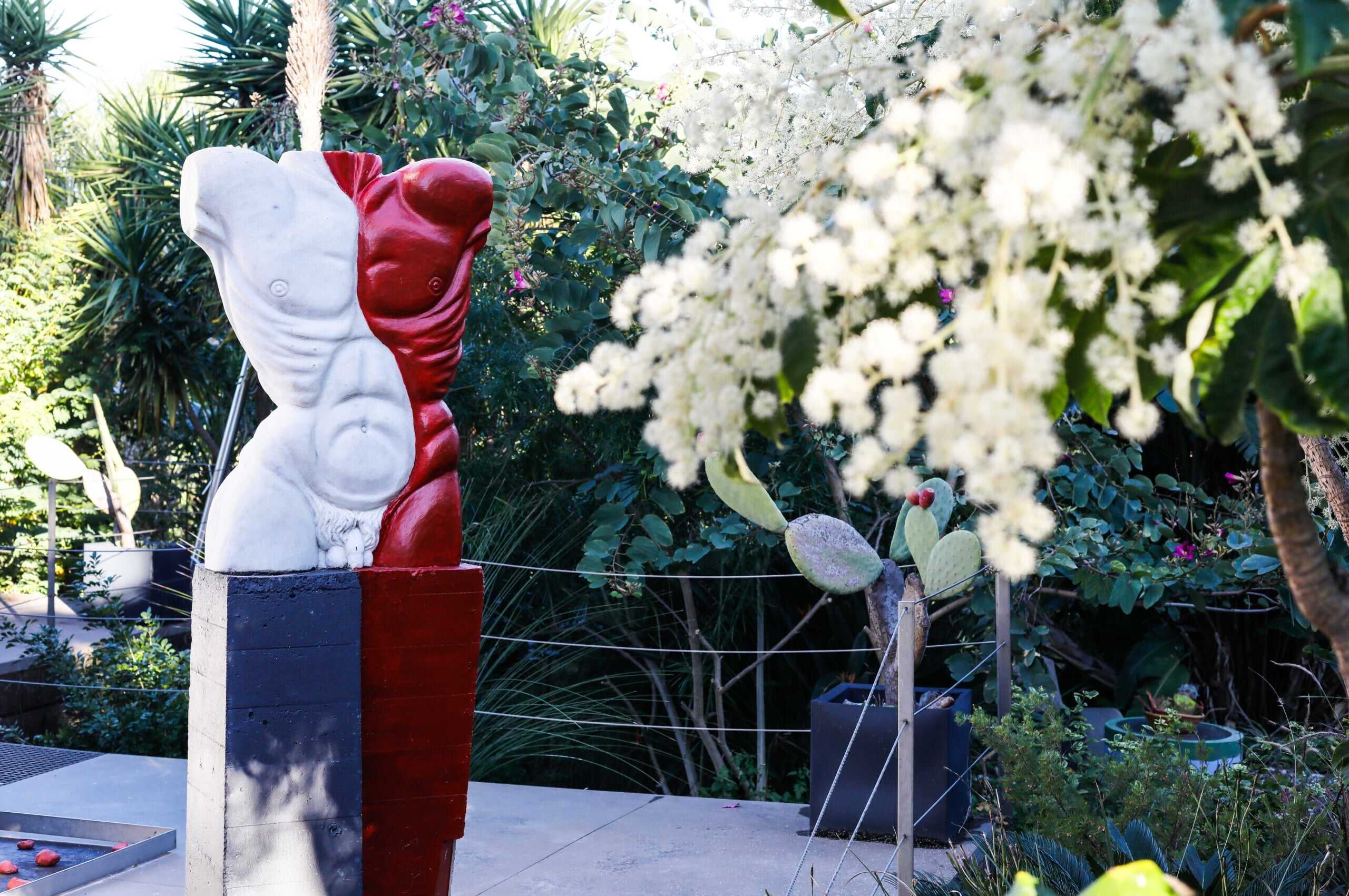 Statua artistica moderna in giardino con piante tropicali e cactus, decorazione esterna di tendenza per case di design.