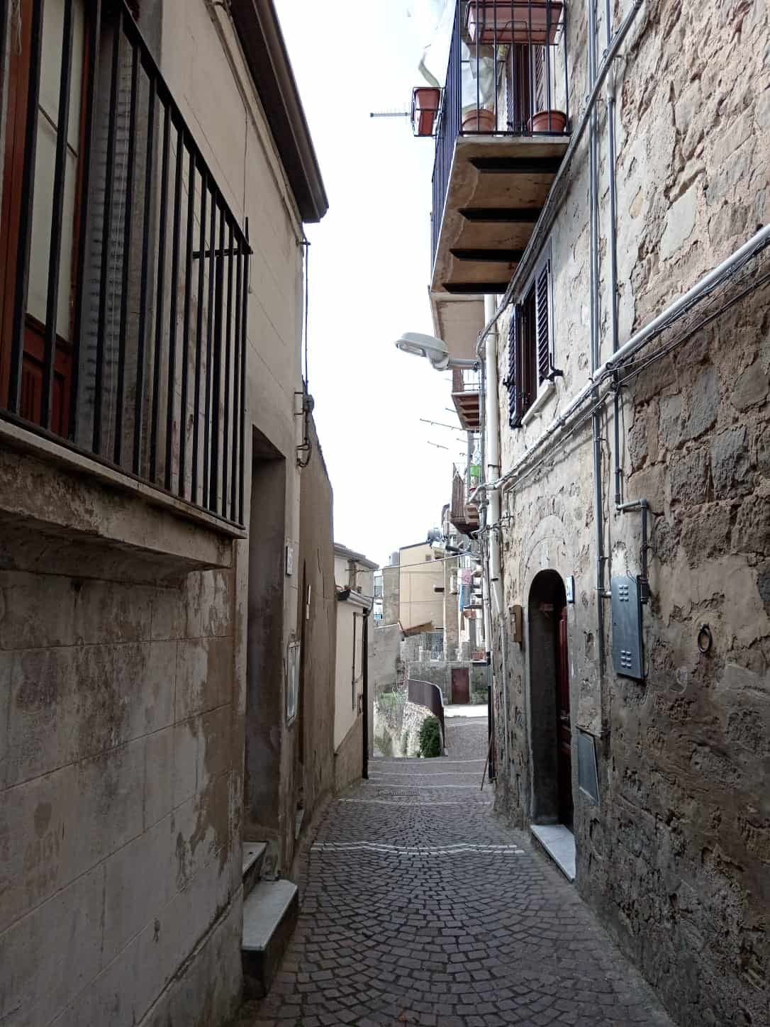 Vicoli storici italiani con case in pietra, dettagli di balconi e strade acciottolate, perfetti per immobile in centro storico.