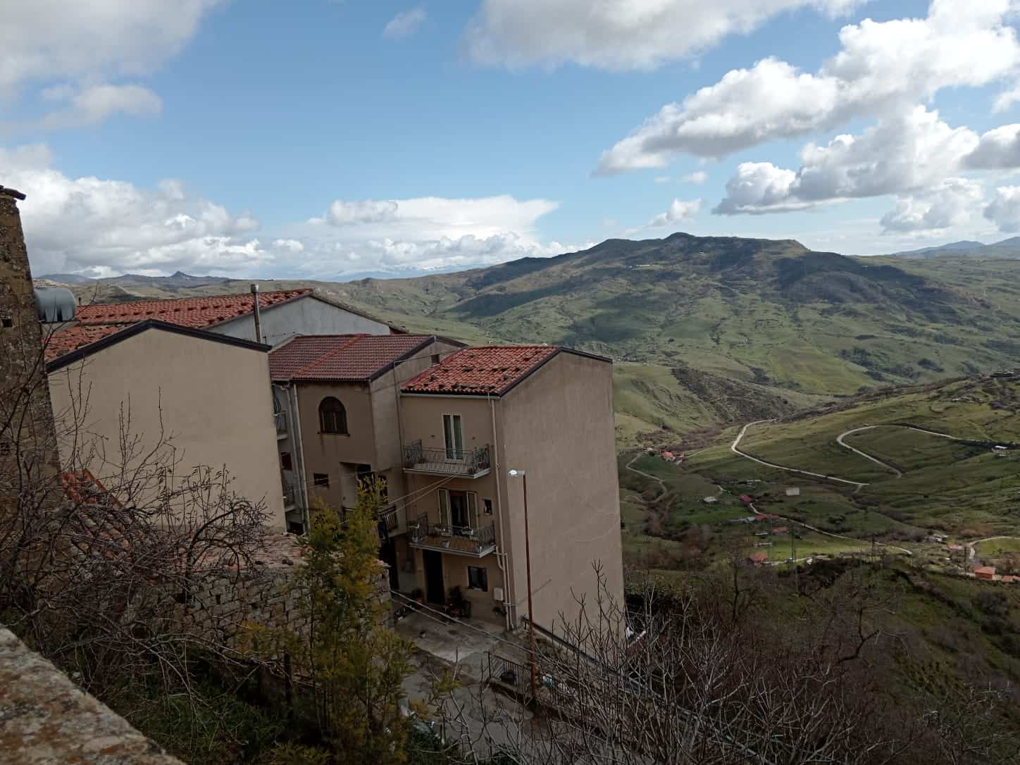 Perspective sulle case in alto con vista panoramica sulle colline verdi e i monti, in un paesaggio rurale tranquillo, ideale per immobili di montagna e residenziali immersi nella natura in Italia.