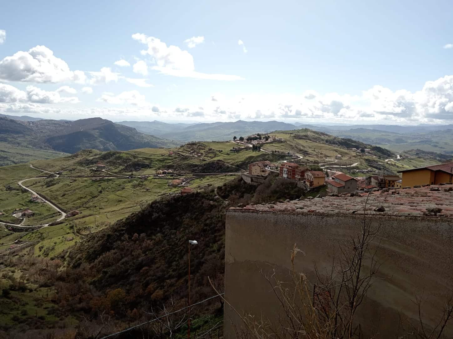 Vista panoramica di un paesaggio collinare con villaggi e strade tortuose tra le verdi colline, ambiente rurale in Toscana, ideale per annunci immobiliari NextCasa.