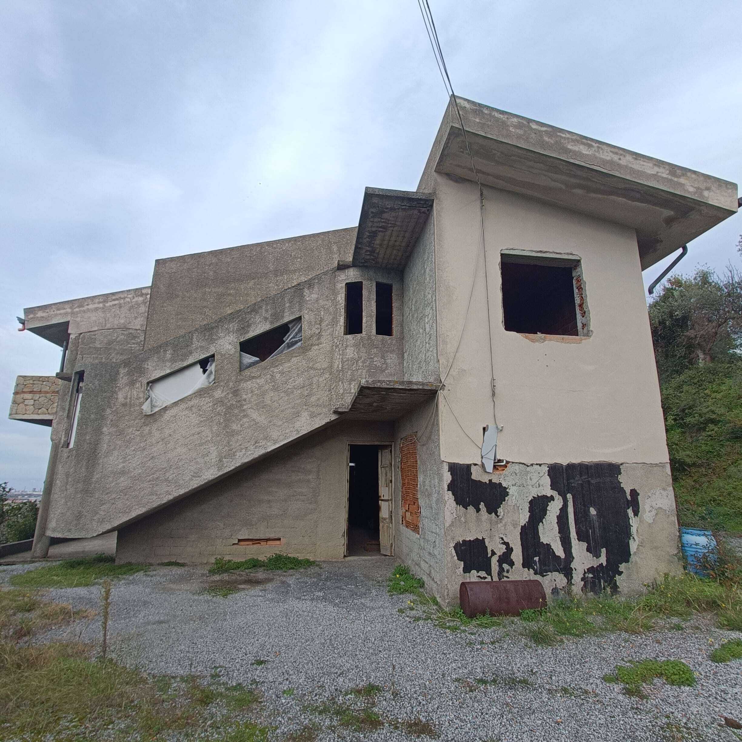 Stabile in costruzione o ristrutturazione con design moderno, pareti in cemento e grandi finestre, pronto per essere personalizzato, situato in una zona verde e tranquilla.