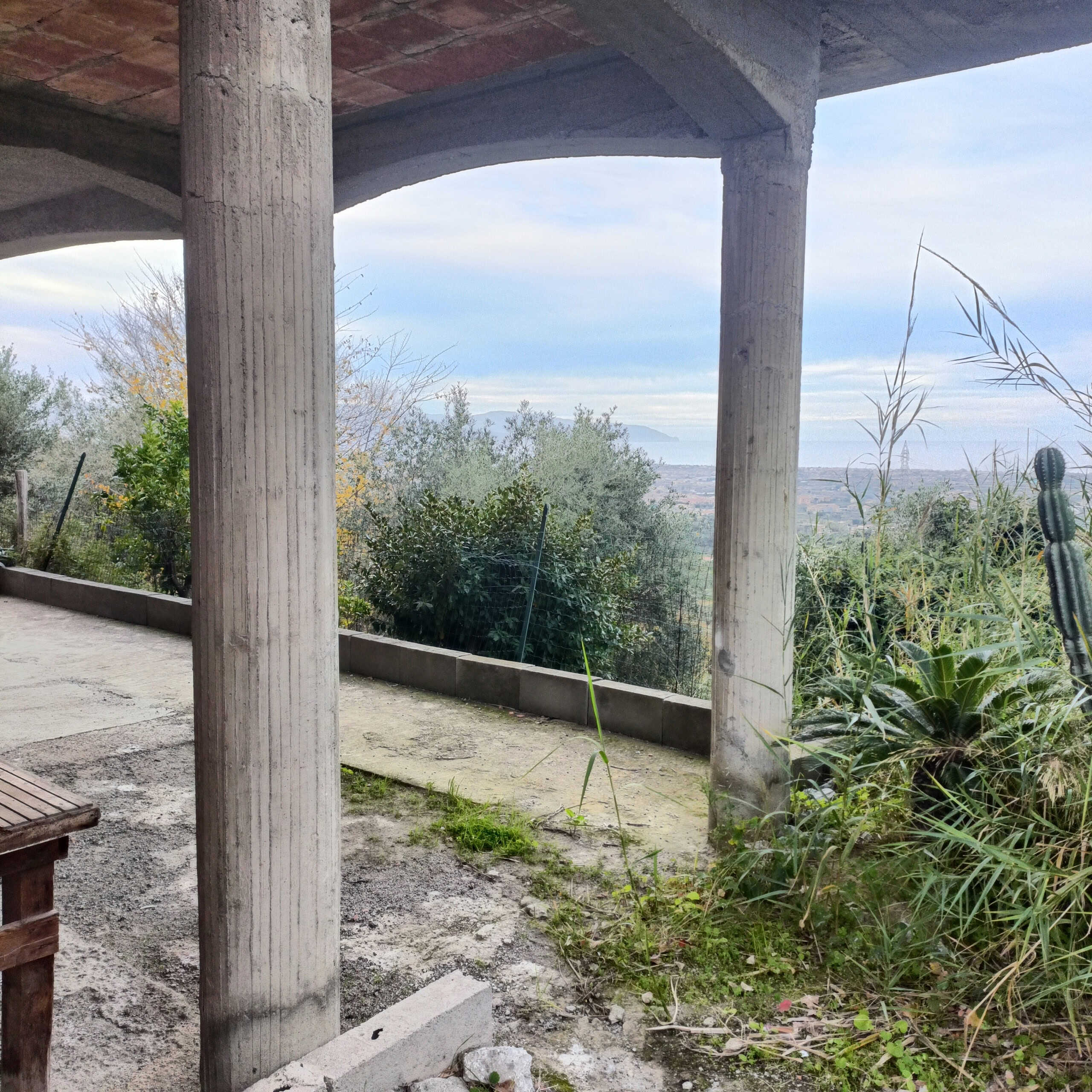 Architettura esterna con colonnato in cemento e vista panoramica natura.
