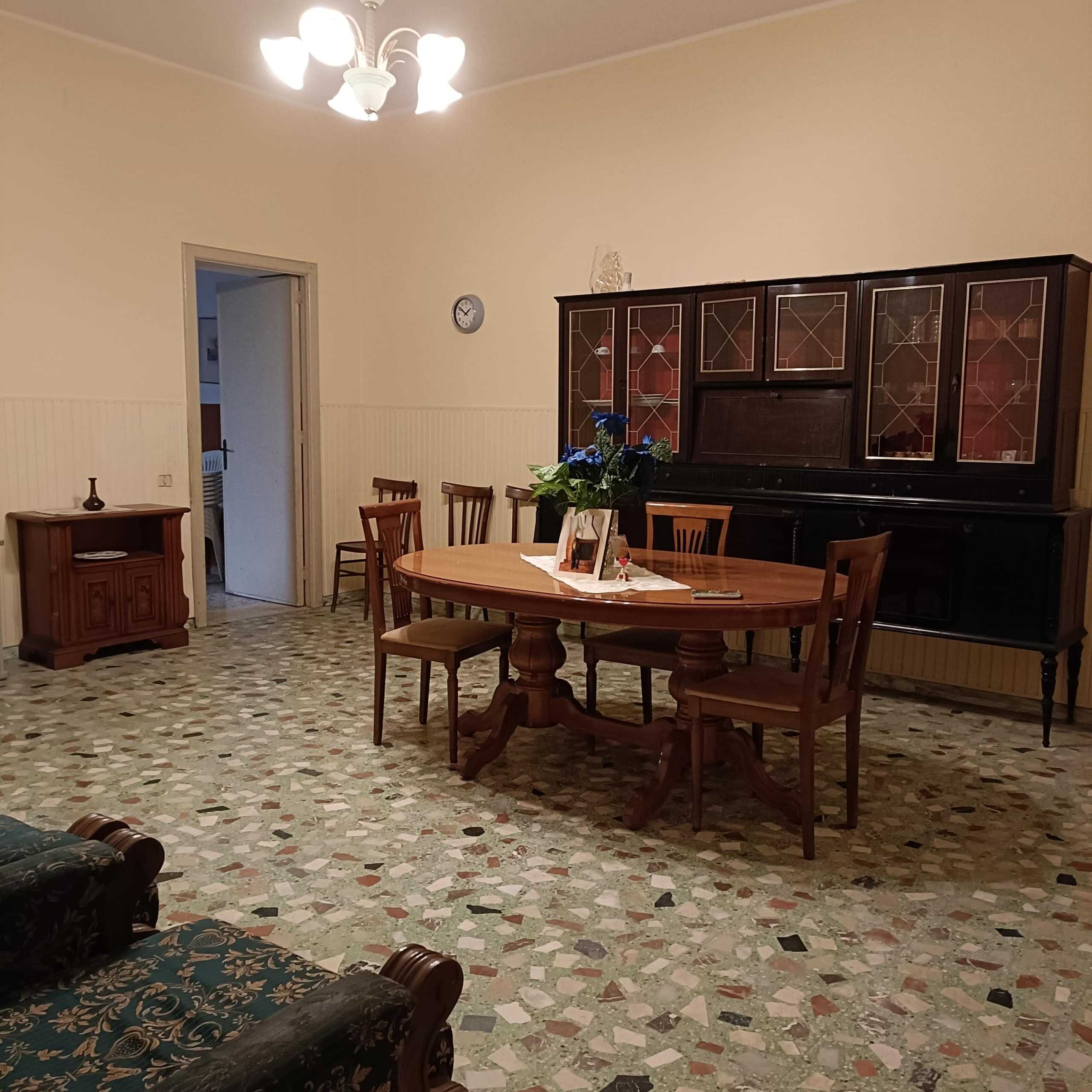 Vecchia sala da pranzo con tavolo in legno, sedie e credenza in stile classico, pavimento in mosaico, ambiente accogliente e arredato con movements per una casa di prossima vendita o affitto.