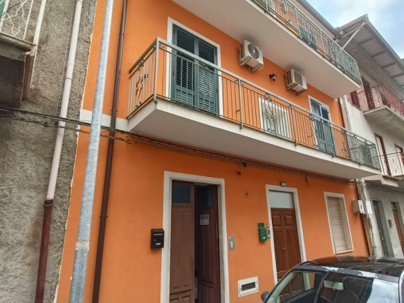 Vila residenziale con facciata arancione, balconi in ferro battuto e aria condizionata, contesto urbano vicino a servizi e parcheggio, stile contemporaneo, ideale per investimento immobiliare.