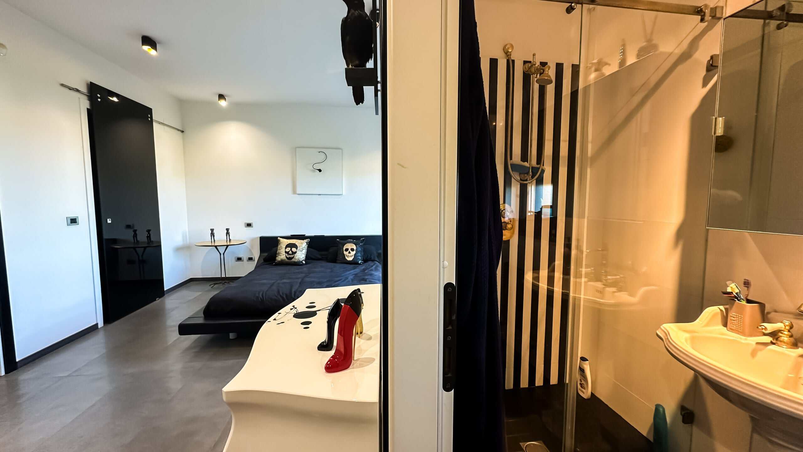 Elegante camera con decorazione moderna e bagno privato, arredi contemporanei, contrasto tra bianco e nero, dettagli di stile e funzionalità, ideale per soggiorni di design.