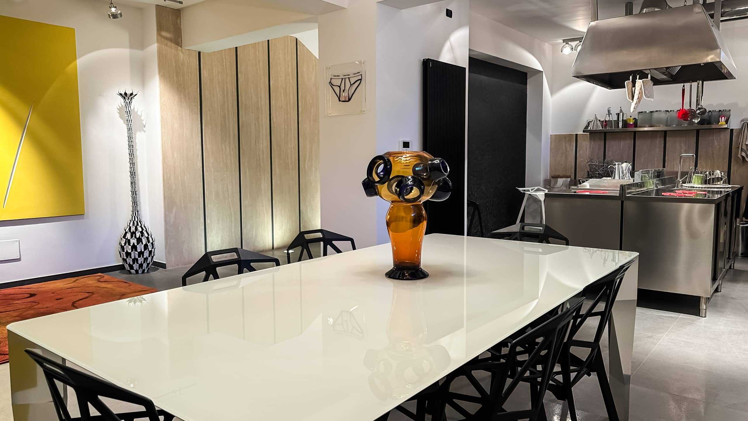Vaso in vetro marrone con design artistico, ambiente moderno con zona pranzo, cucina aperta, elementi di arredo contemporanei, ideale per case di design e living di tendenza.