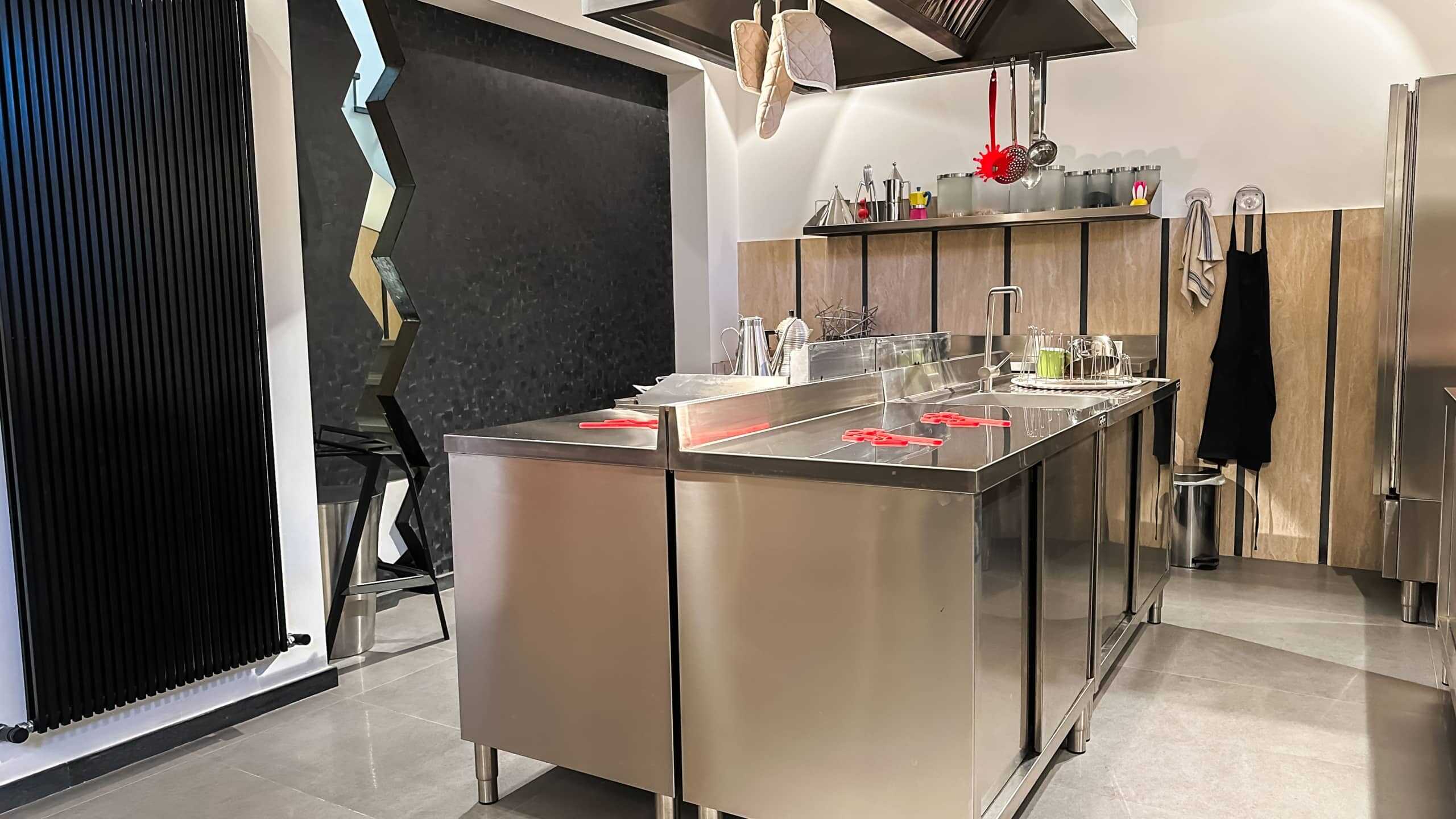 Cucina professionale in stile industriale con piani in acciaio inox, attrezzature moderne e pareti in legno decorativo, idee per arredo cucina commerciale di design.