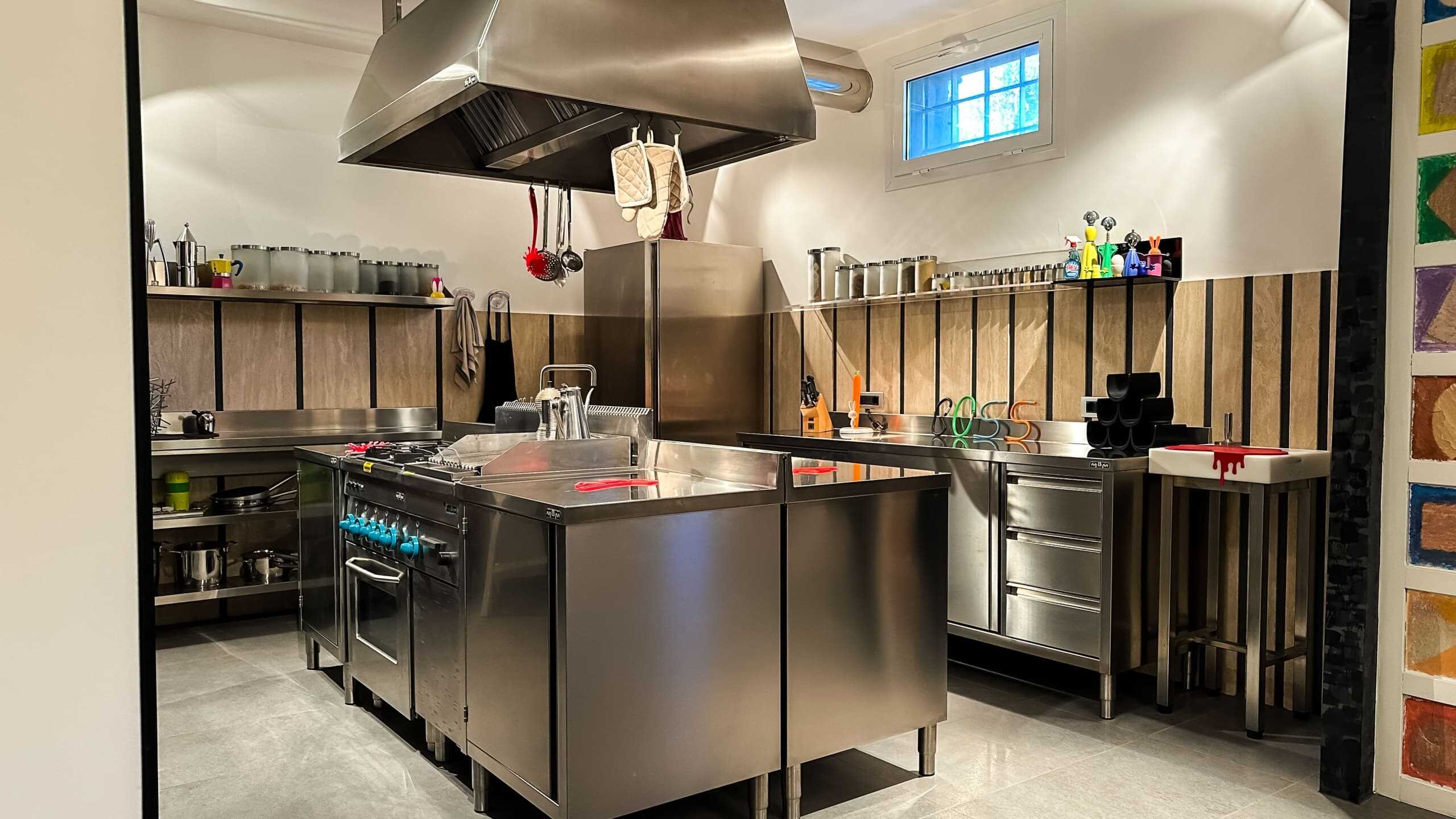 Forno professionale cucina industriale moderna in acciaio inox con area di preparazione e accessori di cucina. Cucina attrezzata con elettrodomestici e utensili professionali in ambiente funzionale e moderno.