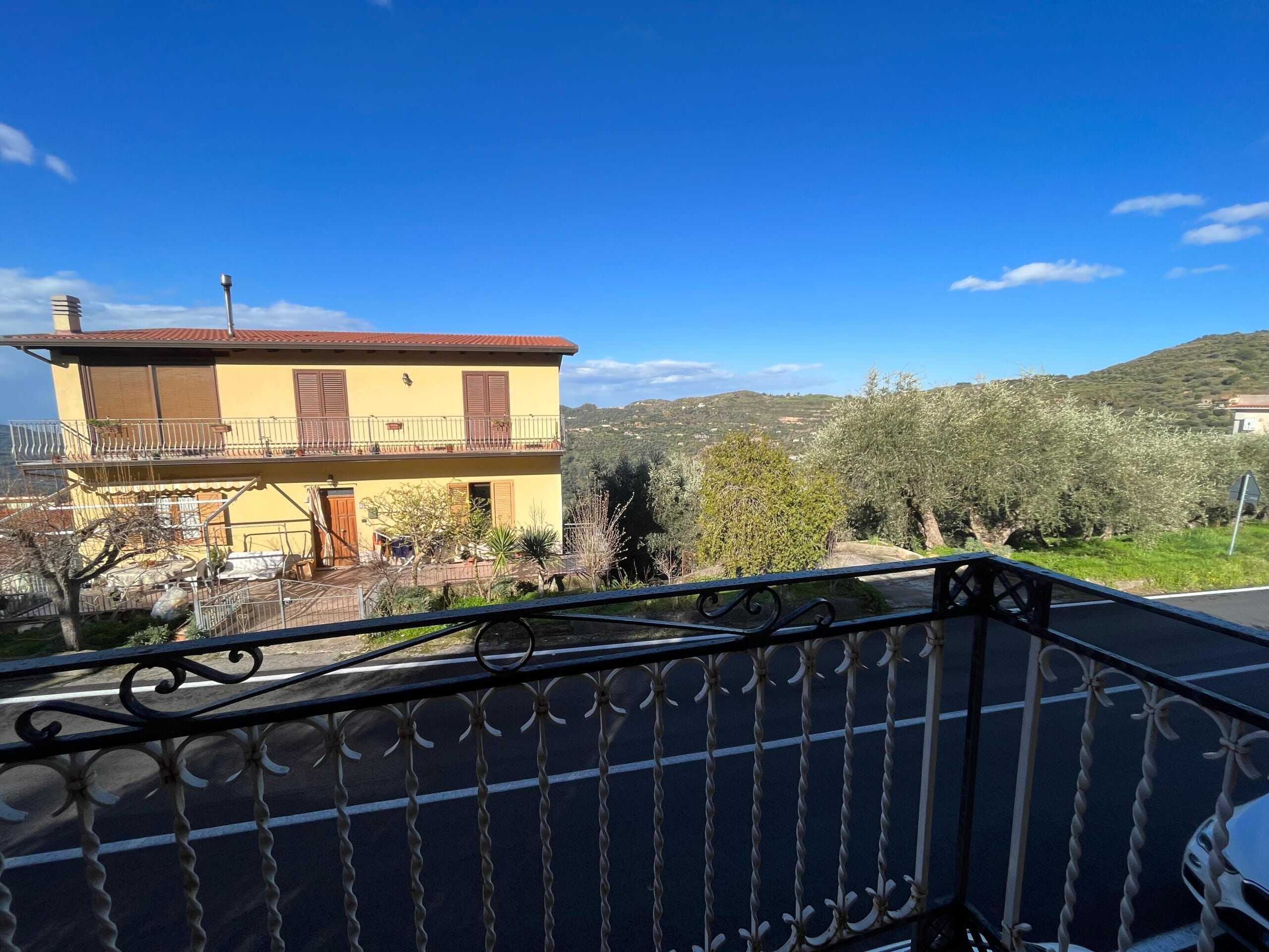 Balcone con vista su casa e paesaggi collinari, con cielo sereno, in una zona residenziale tranquilla, ideale per immobili di NextCasa.