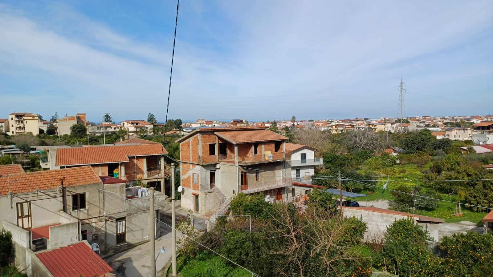 Ville residenziale con case in costruzione e giardini, vista panoramica sulle terrazze e il paesaggio circostante, abitazioni con tetti in terracotta, area verde e infrastrutture urbane in primo piano.