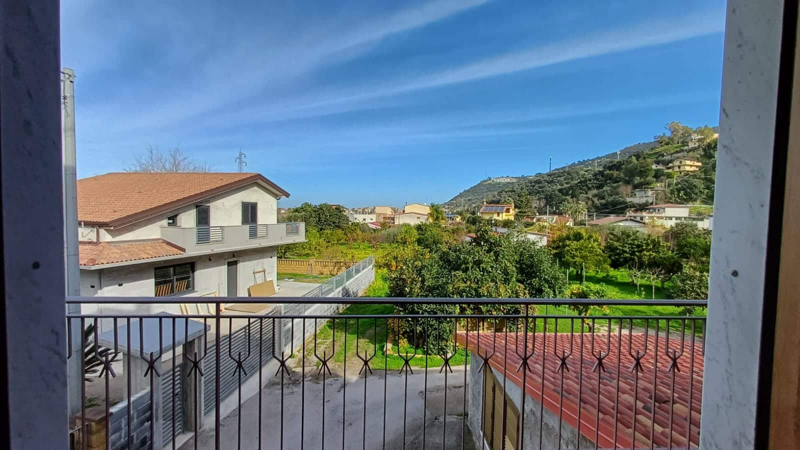 VISTA PANORAMICA SU GIARDINO E ABITAZIONI IN UNA ZONA RESIDENZIALE MODERNA CON MONTAGNE SULLO SFONDO, VISTA DAL BALCONE.