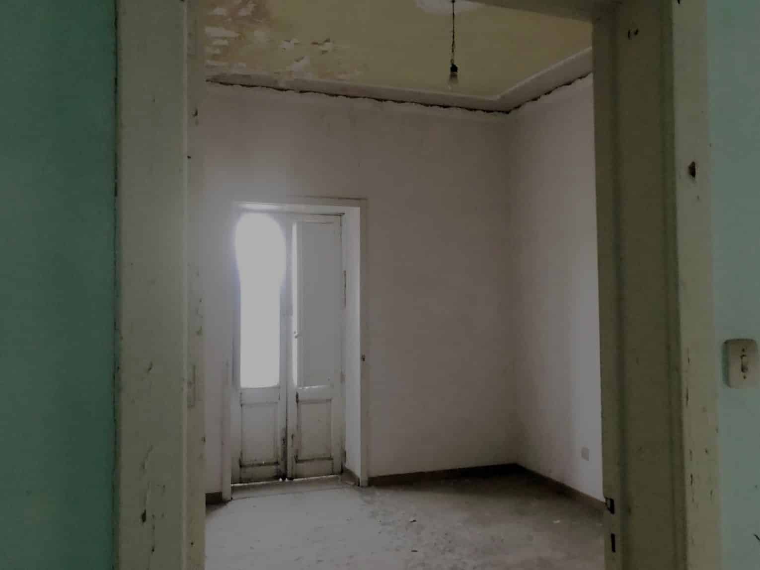 Finestra con porta in legno in una stanza in fase di ristrutturazione, ambiente da rinnovare, spazio vuoto, lavori di costruzione o restauro, interni di casa, immobile in aggiornamento.