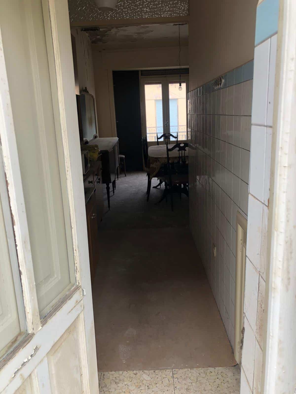 Antico appartamento in vendita con cucina e soggiorno, vista su balcone, caratterizzato da un arredo vintage e dettagli storici, ideale per chi cerca un investimento immobiliare a Firenze.