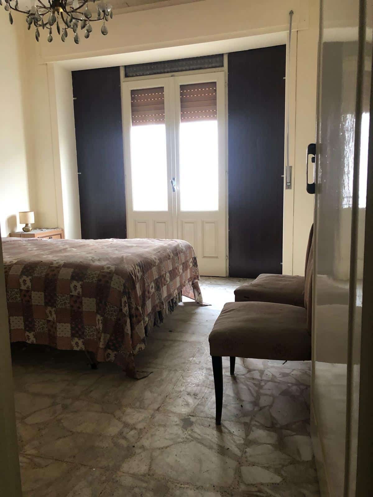 Camere da letto in affitto con arredi tradizionali e grandi finestre con tende scure, soluzione ideale per affitti casa a lungo termine.